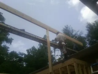 Carpenter setting a ridge beam over a new addition frame — Ice Dam Removal by Roofing Brothers in Oslo