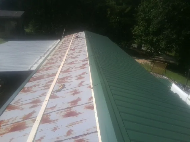 Old rusted panels beside newly installed green metal roofing — Wind Damage Roof Repair by Roofing Brothers in Oslo