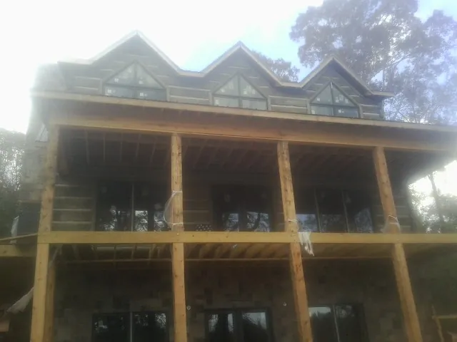 Dormers and porch framing on a large log home under construction — Roof Coating work by our crew in Oslo