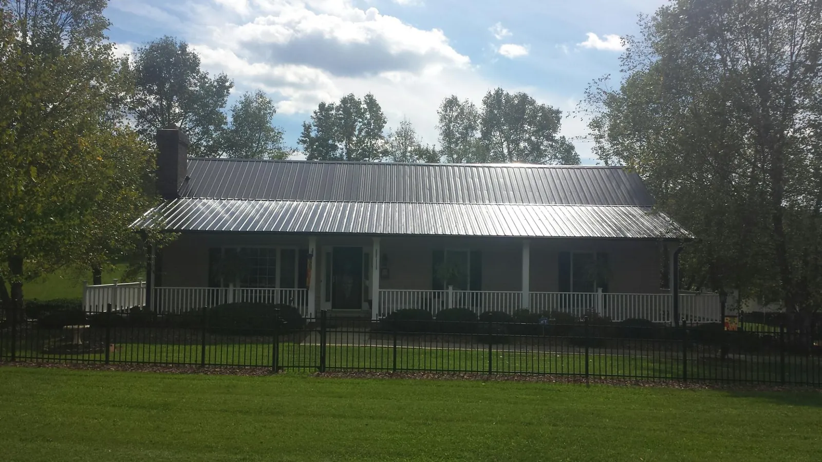 Gray metal roof on a brick ranch with a full width front porch — Gutter Guard Installation work by our crew in Oslo